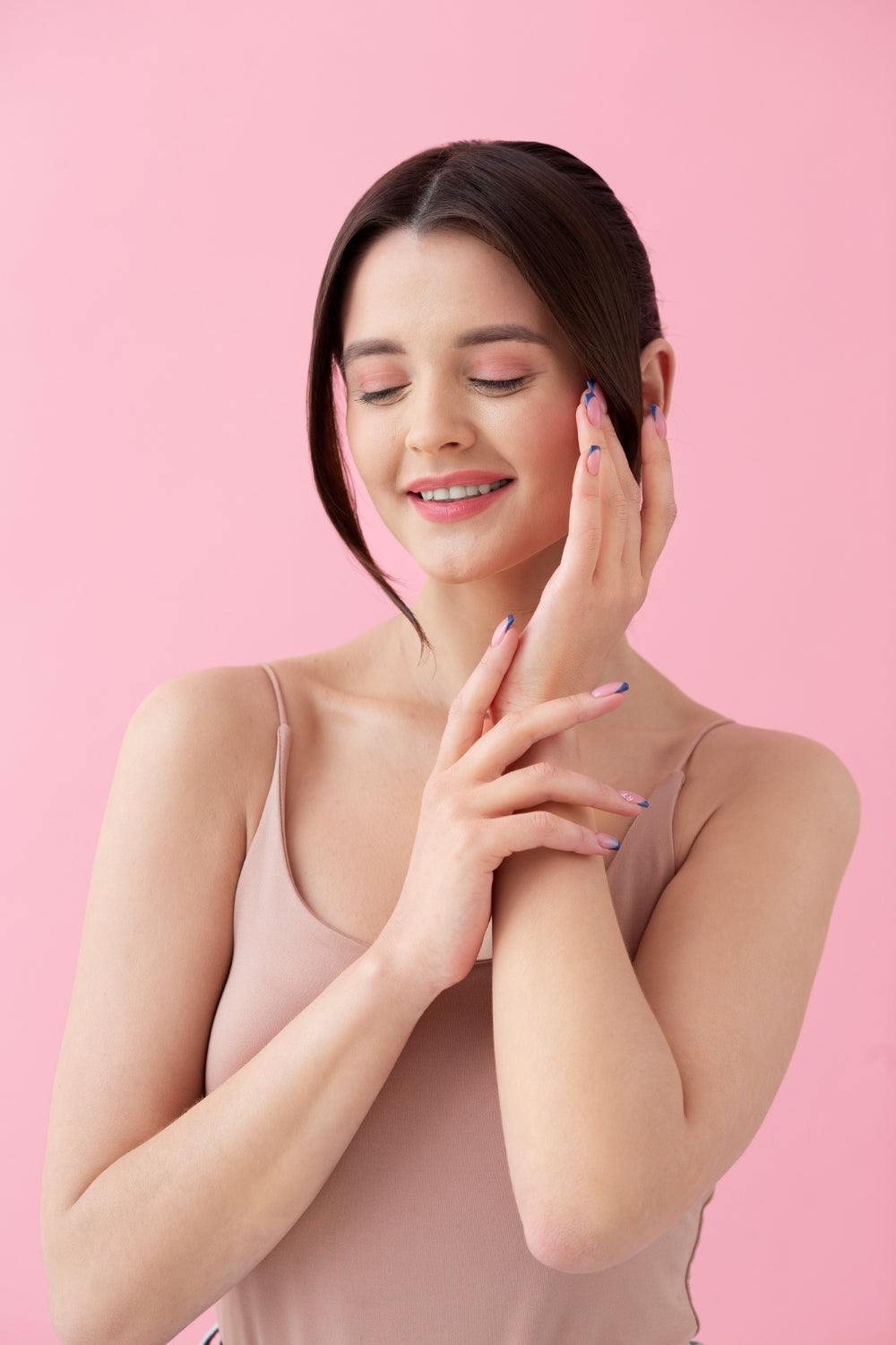 Woman touching her face against a pink background